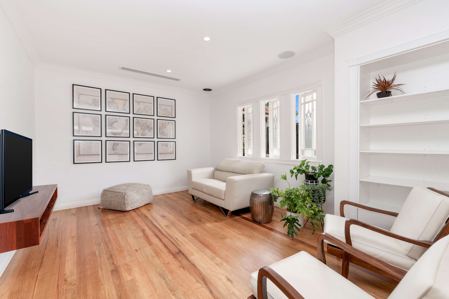 Modernes Wohnzimmer mit cremefarbener Couch, Sesseln und Karten-Prints.