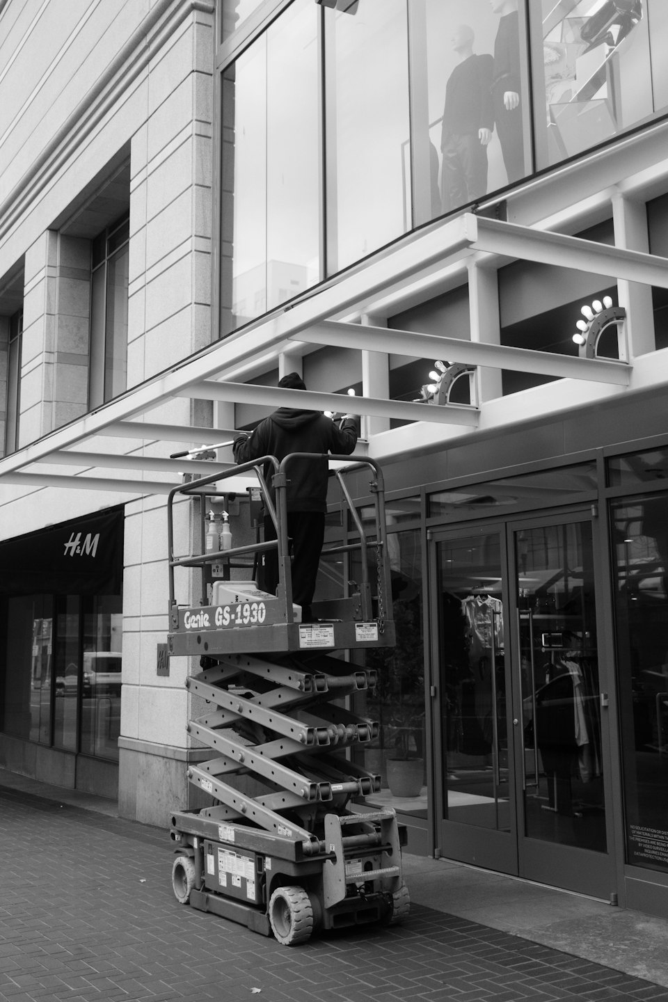 Arbeiter auf Scherenbühne wartet an einem Geschäftsgebäude.
